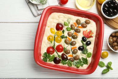 Photo of Raw focaccia with vegetables, olives and spices on white wooden table, flat lay. Space for text