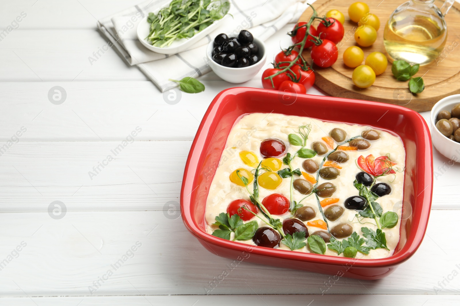 Raw focaccia with vegetables, olives and spices on white wooden table, closeup. Space for text Photo of Raw focaccia with vegetables, olives and spices on white wooden table, closeup. Space for text