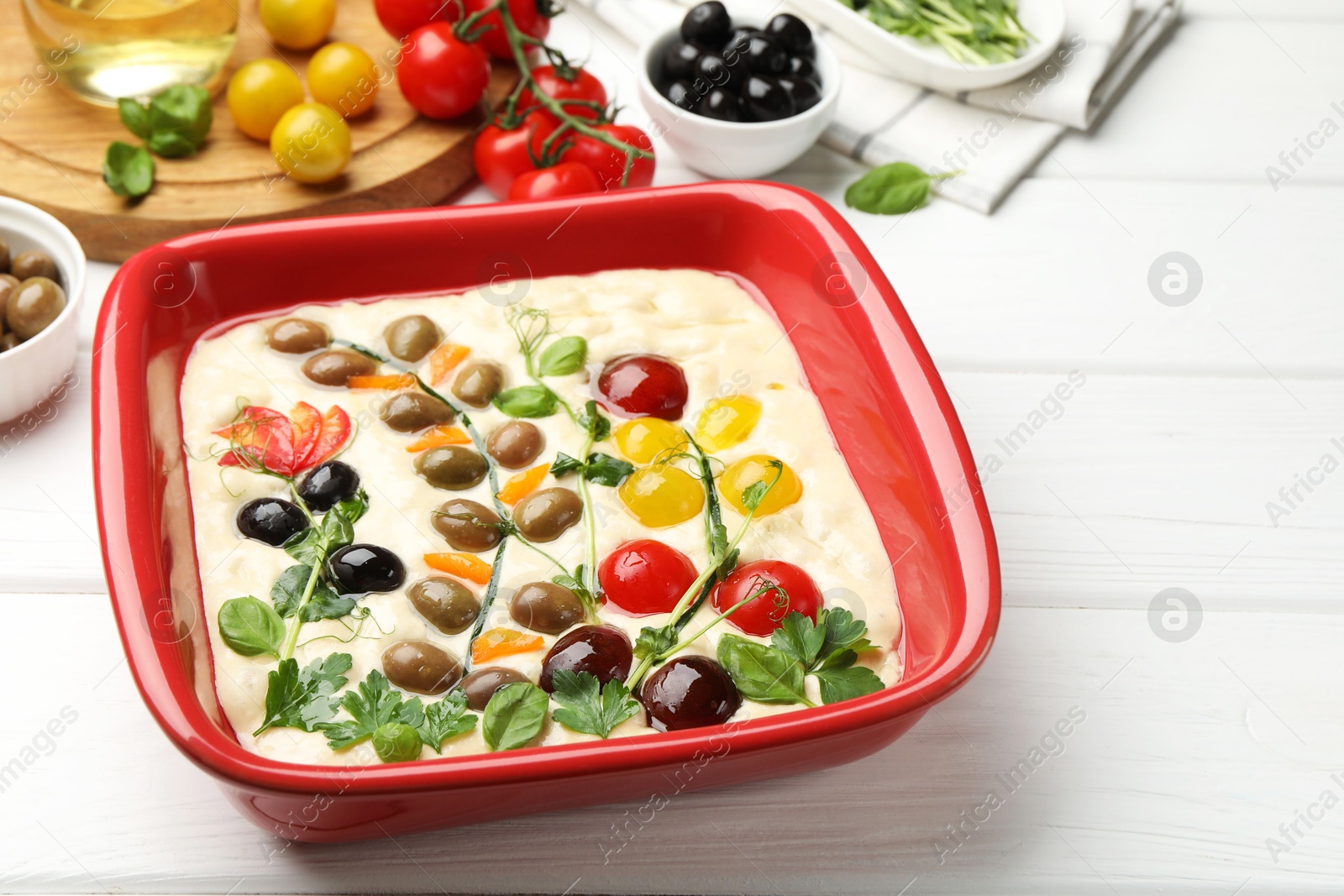 Raw focaccia with vegetables, olives and spices on white wooden table, closeup. Space for text Photo of Raw focaccia with vegetables, olives and spices on white wooden table, closeup. Space for text