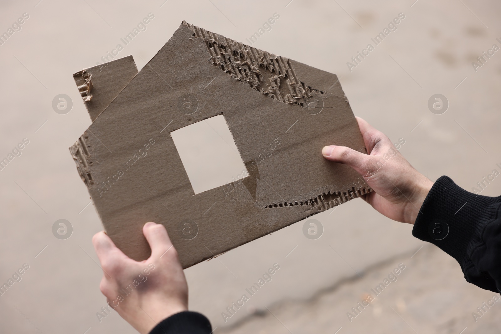 Homeless man with carton house figure outdoors, closeup Photo of Homeless man with carton house figure outdoors, closeup