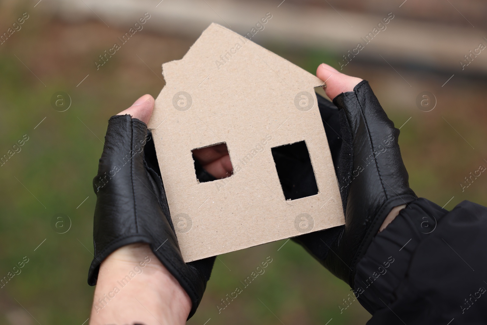 Homeless man with carton house figure outdoors, closeup Photo of Homeless man with carton house figure outdoors, closeup