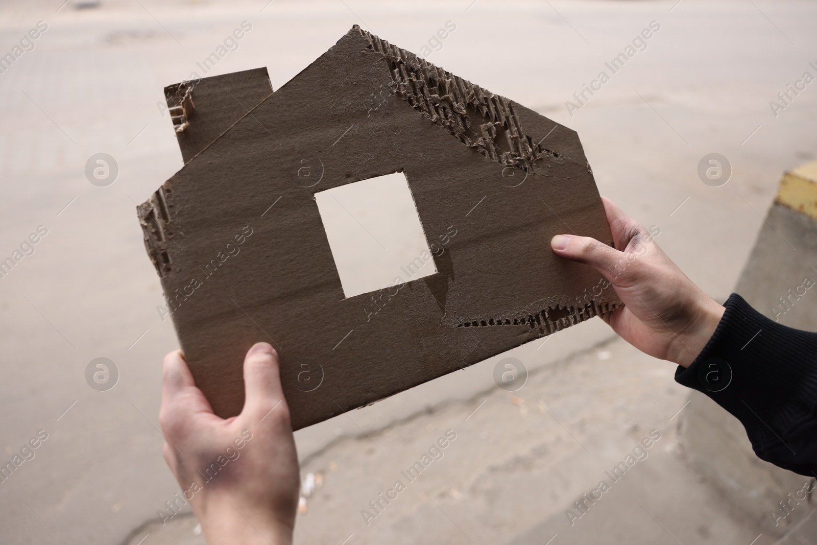 Homeless man with carton house figure outdoors, closeup Photo of Homeless man with carton house figure outdoors, closeup