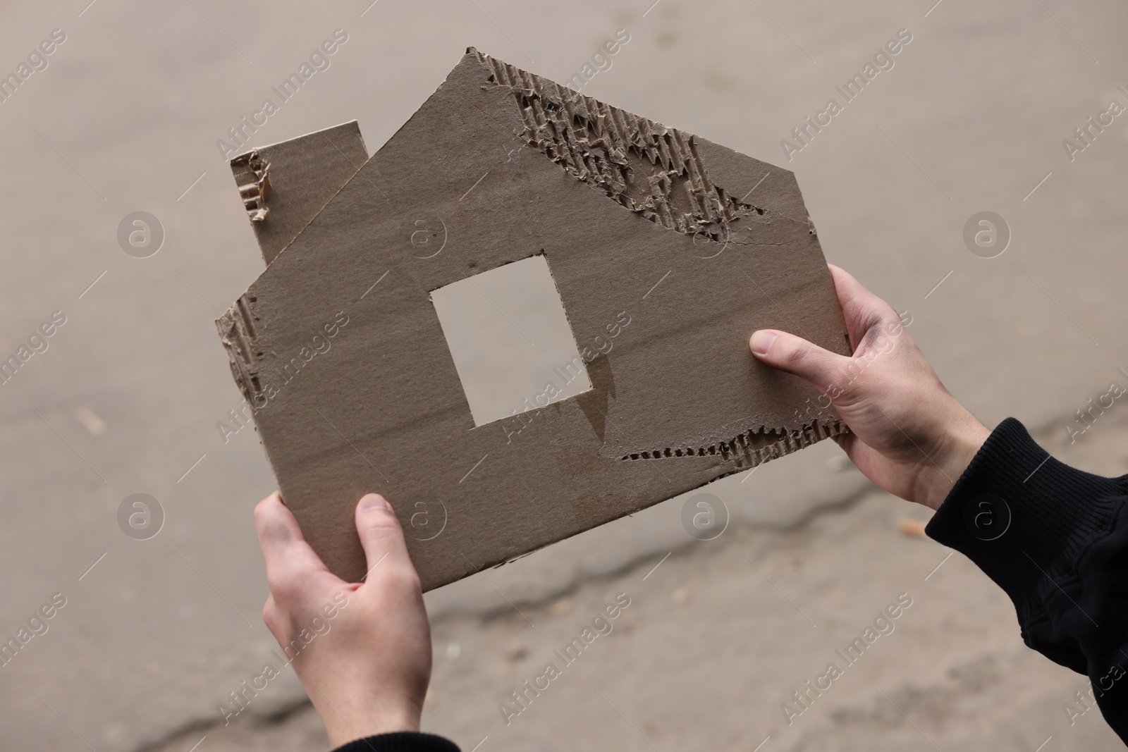 Homeless man with carton house figure outdoors, closeup Photo of Homeless man with carton house figure outdoors, closeup