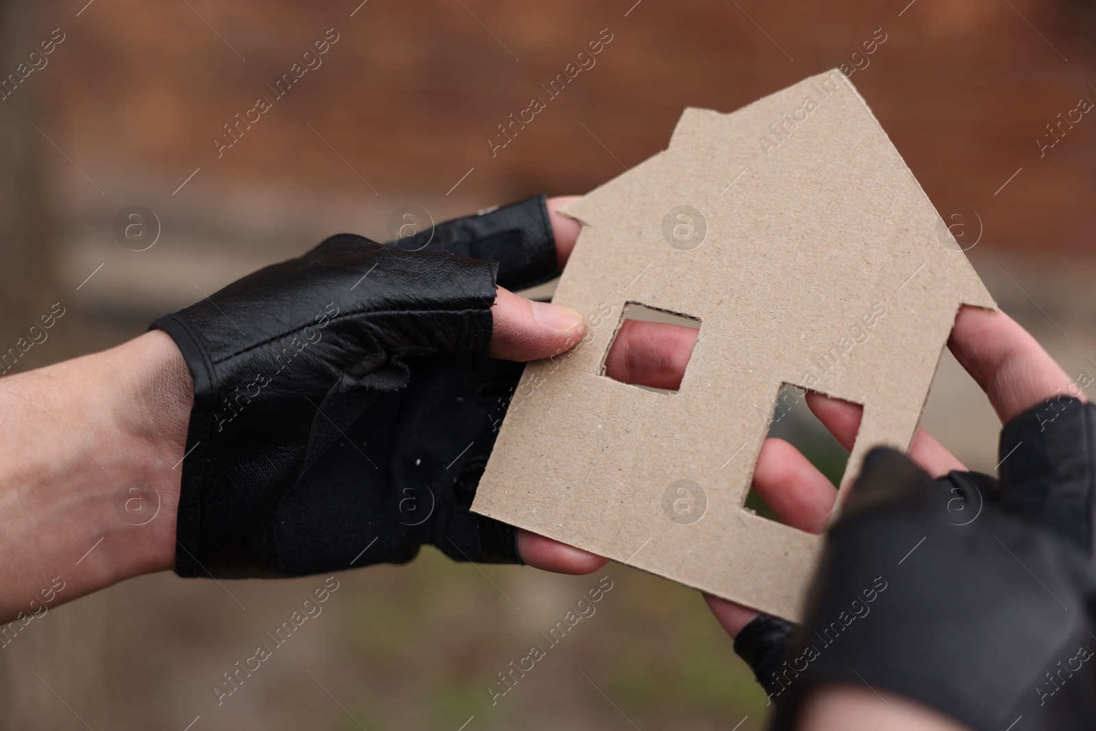 Homeless man with carton house figure outdoors, closeup Photo of Homeless man with carton house figure outdoors, closeup