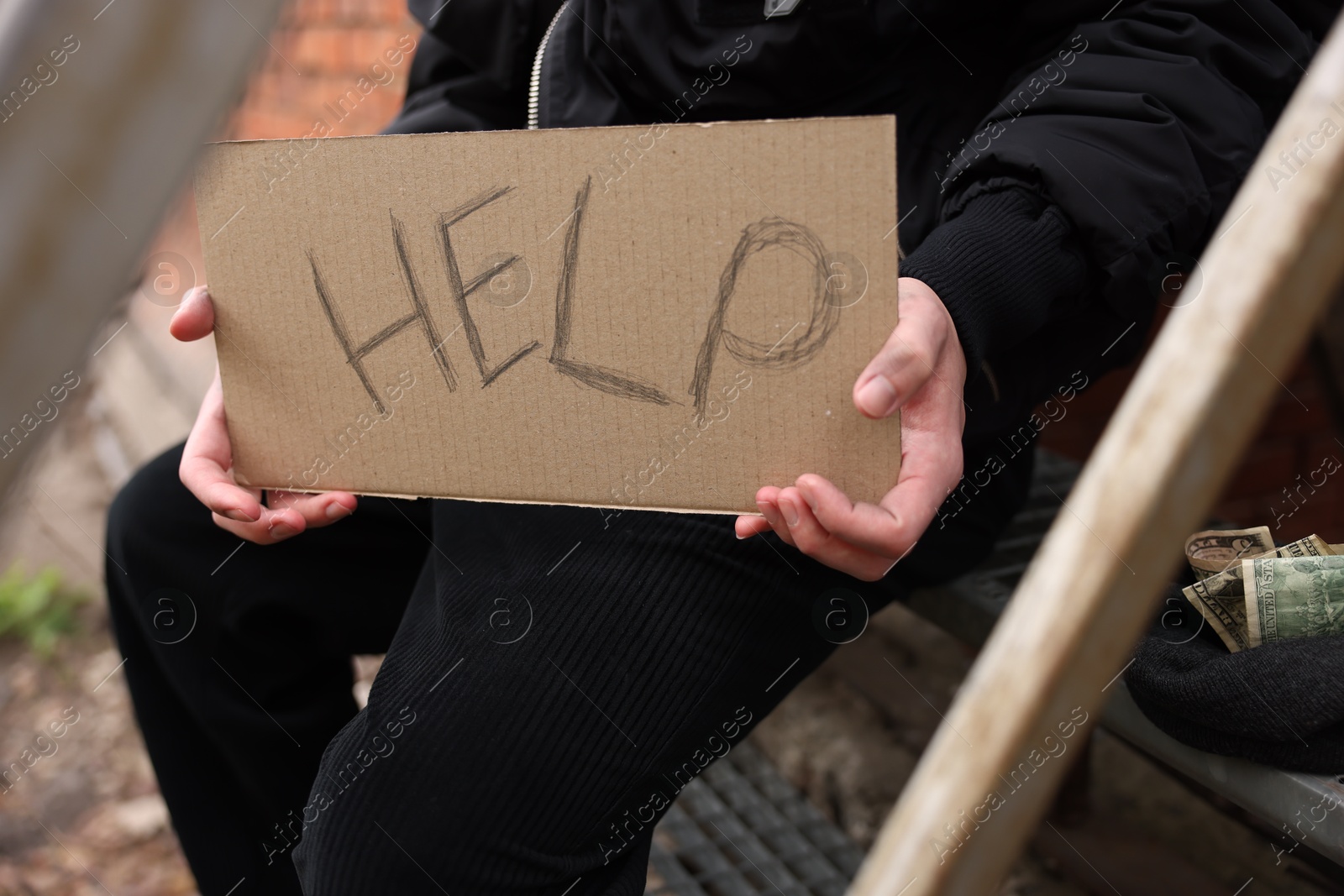 Homeless man holding sign with word Help outdoors, closeup Photo of Homeless man holding sign with word Help outdoors, closeup