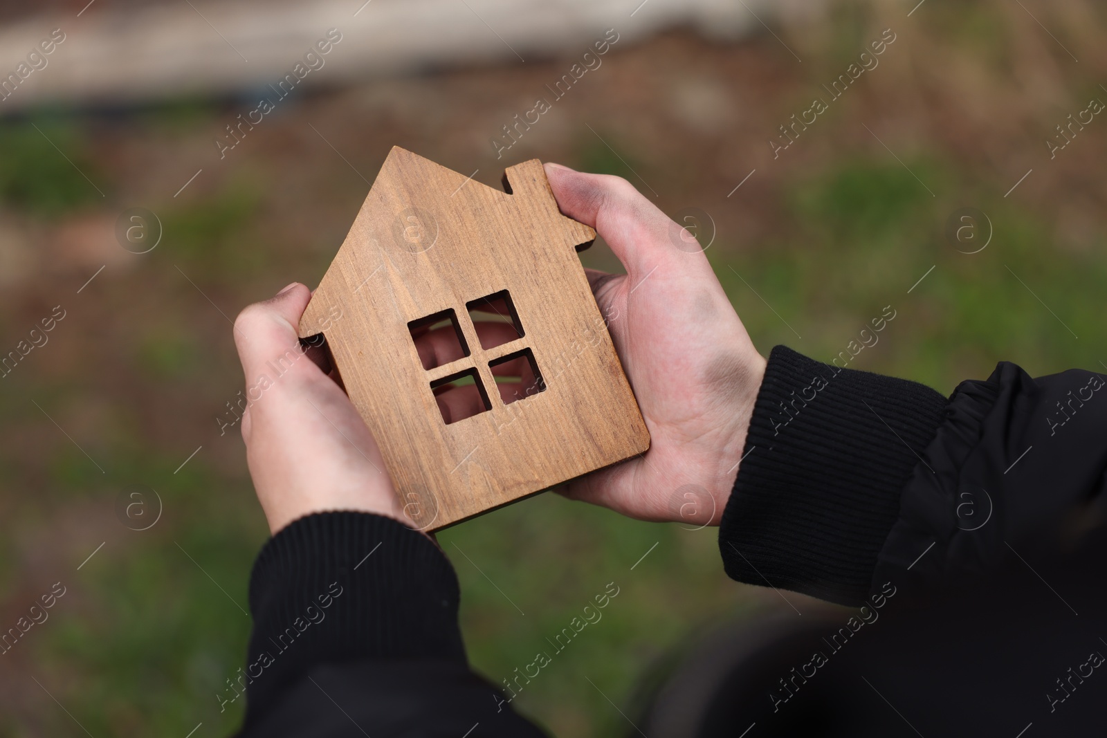 Homeless man with wooden house figure outdoors, closeup Photo of Homeless man with wooden house figure outdoors, closeup