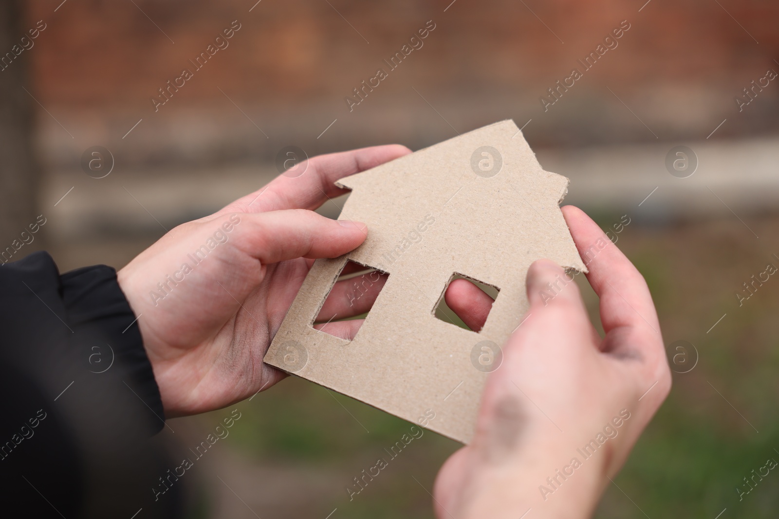 Homeless man with carton house figure outdoors, closeup Photo of Homeless man with carton house figure outdoors, closeup