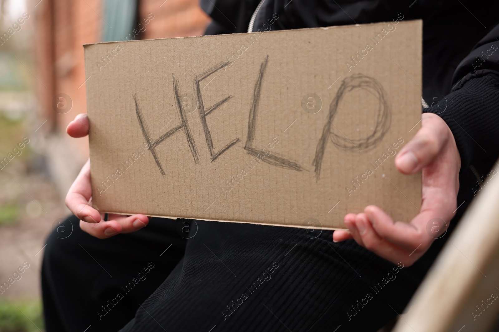 Homeless man holding sign with word Help outdoors, closeup Photo of Homeless man holding sign with word Help outdoors, closeup