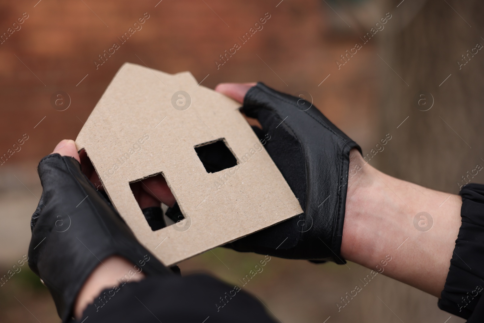 Homeless man with carton house figure outdoors, closeup Photo of Homeless man with carton house figure outdoors, closeup