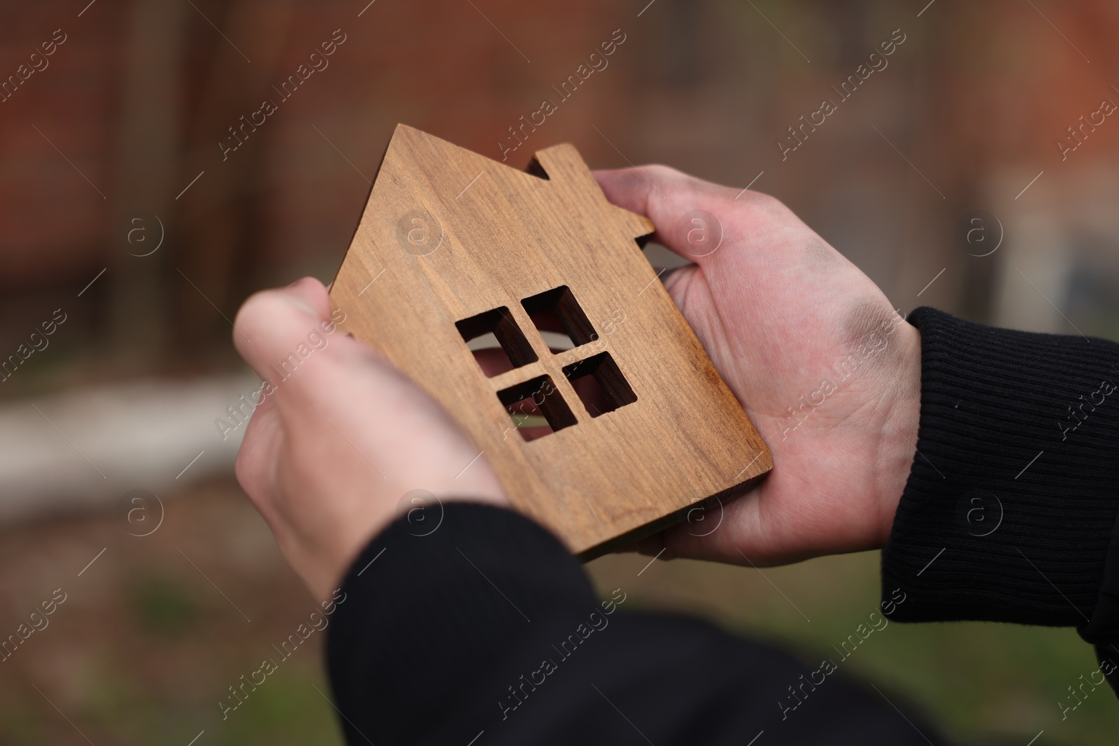 Homeless man with wooden house figure outdoors, closeup Photo of Homeless man with wooden house figure outdoors, closeup