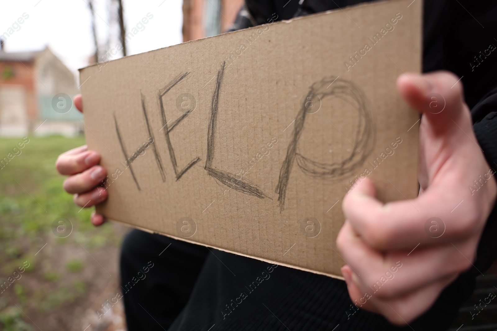 Homeless man holding sign with word Help outdoors, closeup Photo of Homeless man holding sign with word Help outdoors, closeup