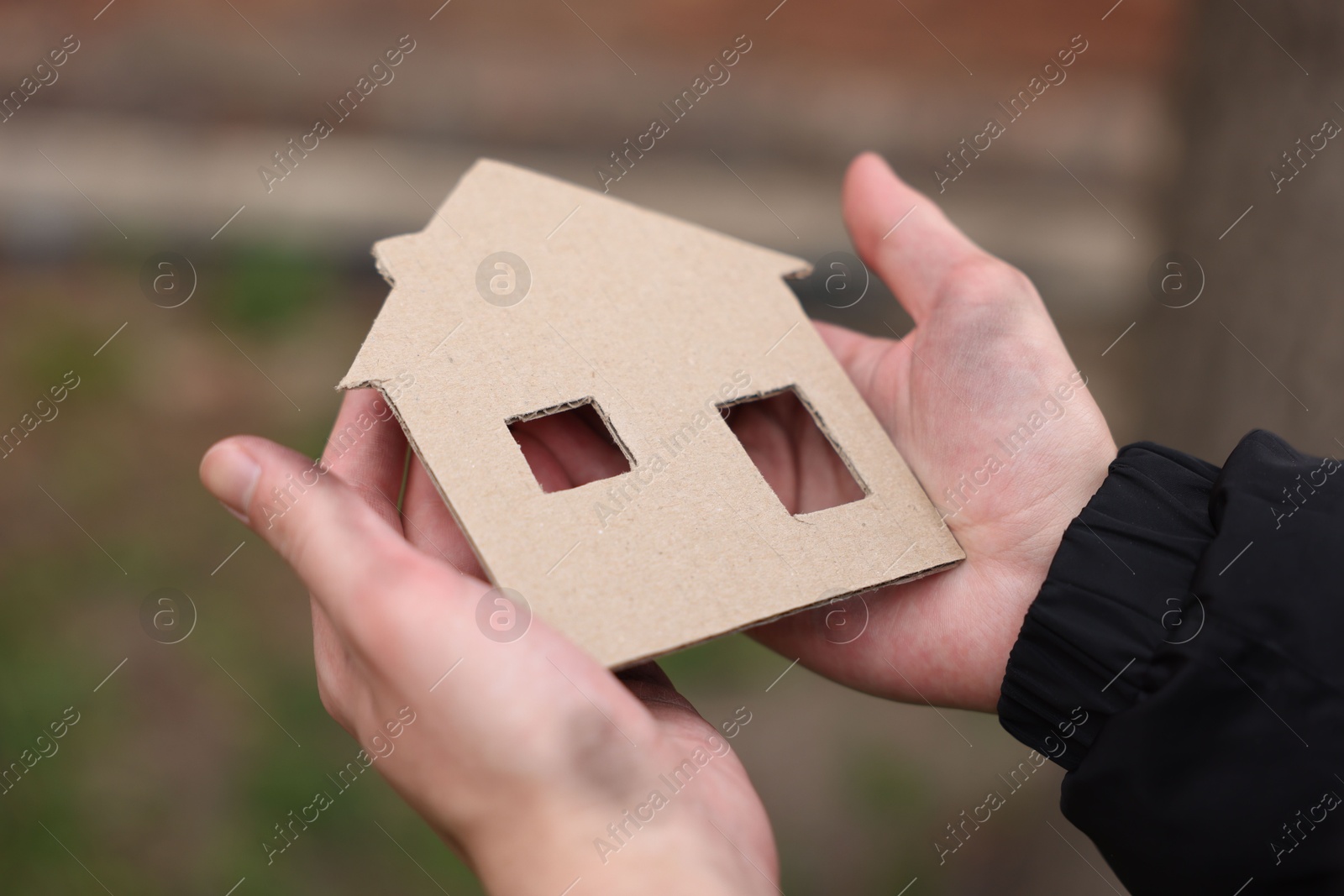 Homeless man with carton house figure outdoors, closeup Photo of Homeless man with carton house figure outdoors, closeup