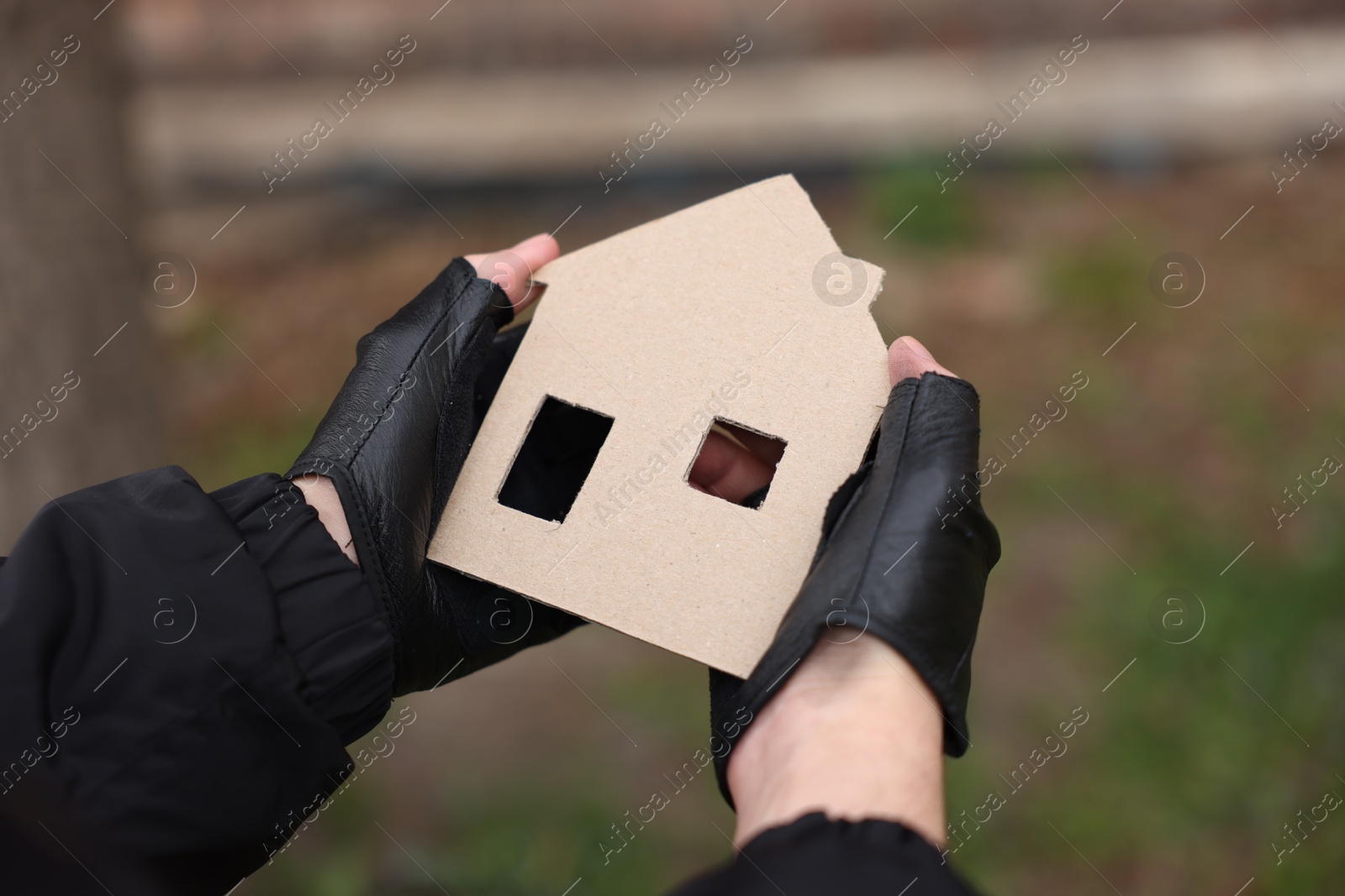 Homeless man with carton house figure outdoors, closeup Photo of Homeless man with carton house figure outdoors, closeup
