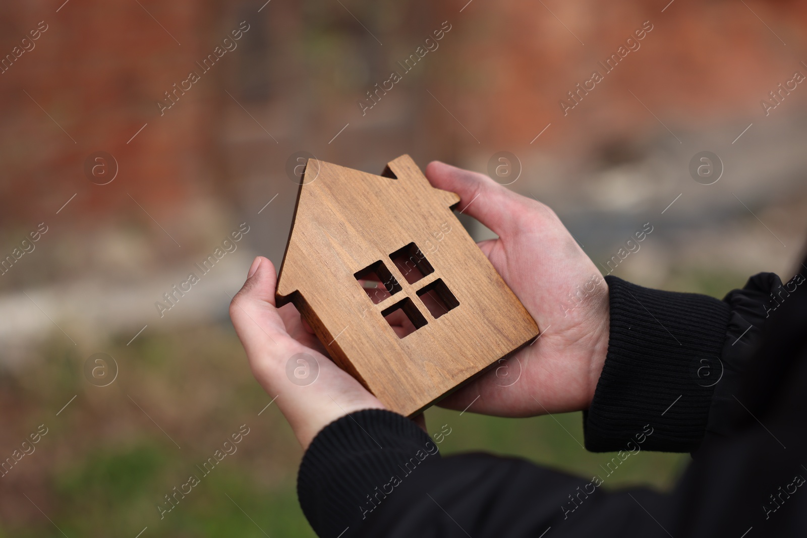 Homeless man with wooden house figure outdoors, closeup Photo of Homeless man with wooden house figure outdoors, closeup