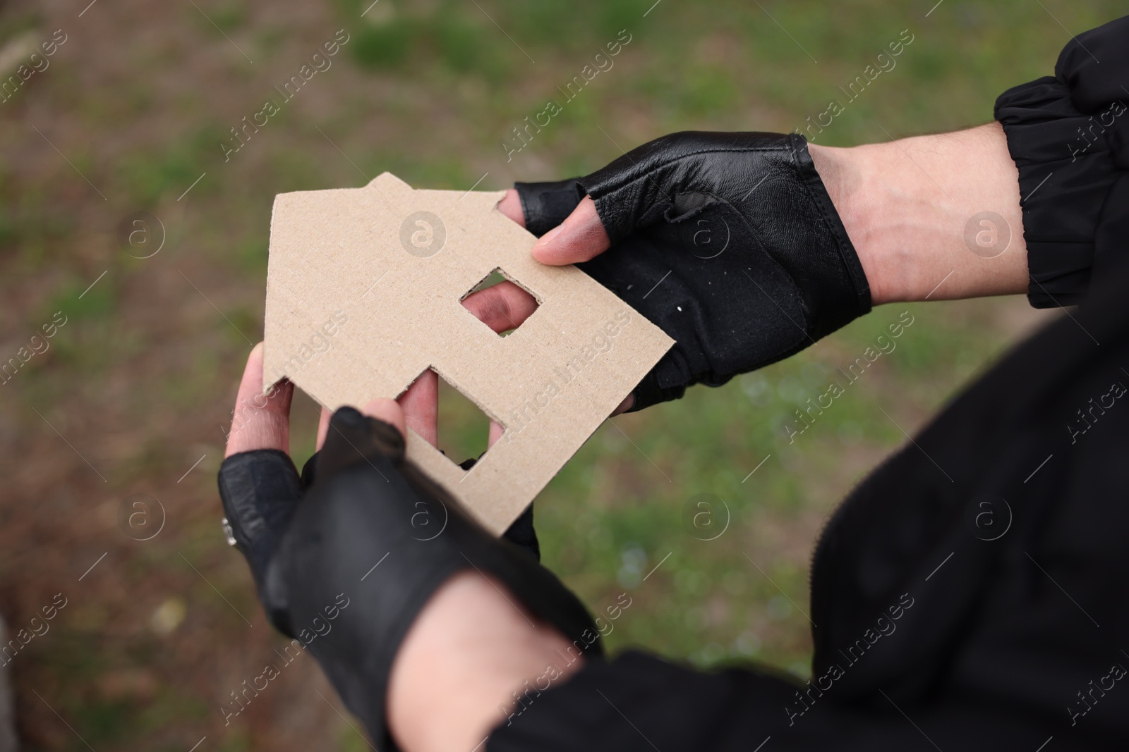 Homeless man with carton house figure outdoors, closeup Photo of Homeless man with carton house figure outdoors, closeup