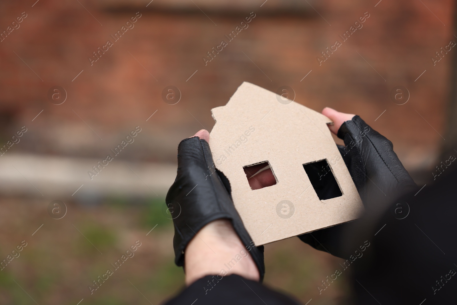Homeless man with carton house figure outdoors, closeup Photo of Homeless man with carton house figure outdoors, closeup