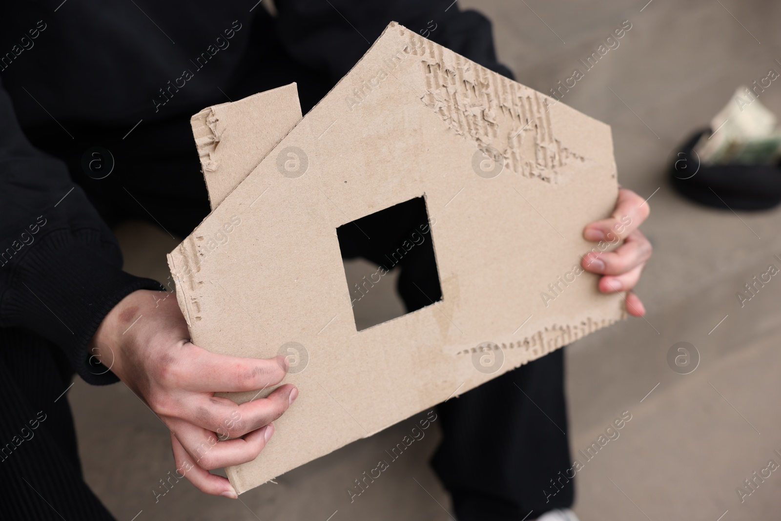 Homeless man with carton house figure outdoors, closeup Photo of Homeless man with carton house figure outdoors, closeup
