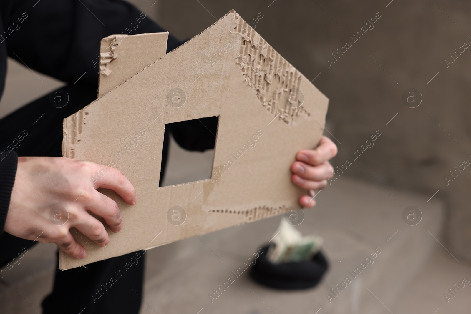 Homeless man with carton house figure outdoors, closeup Photo of Homeless man with carton house figure outdoors, closeup