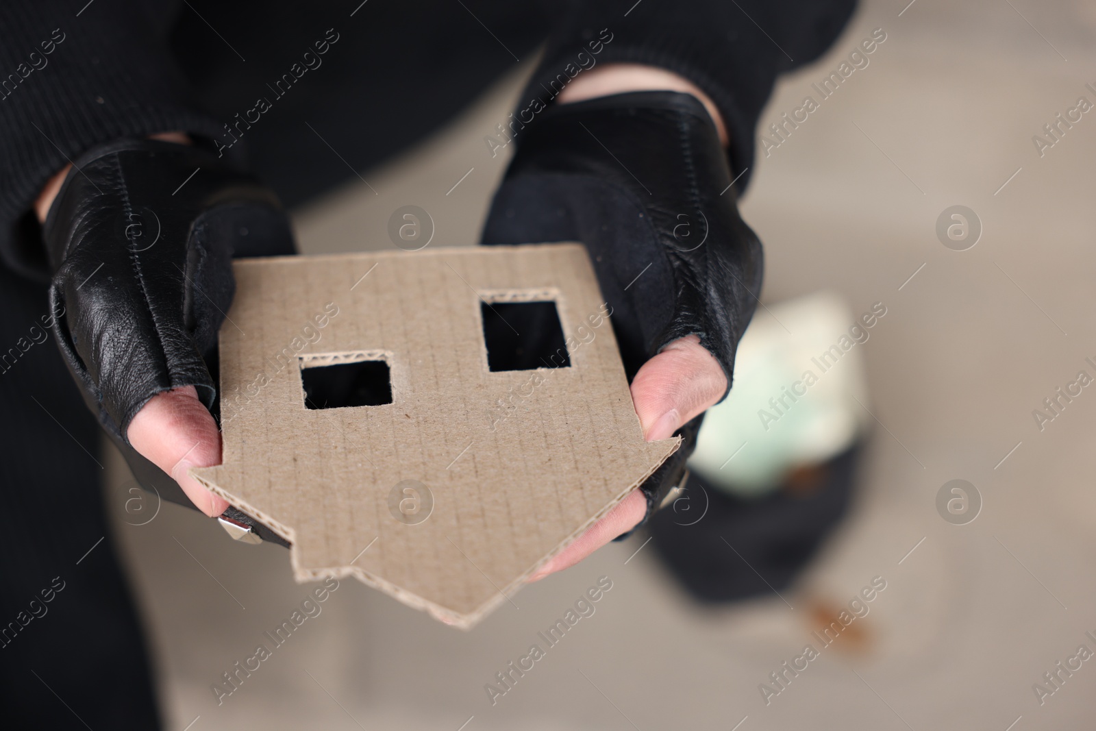 Homeless man with carton house figure outdoors, closeup Photo of Homeless man with carton house figure outdoors, closeup