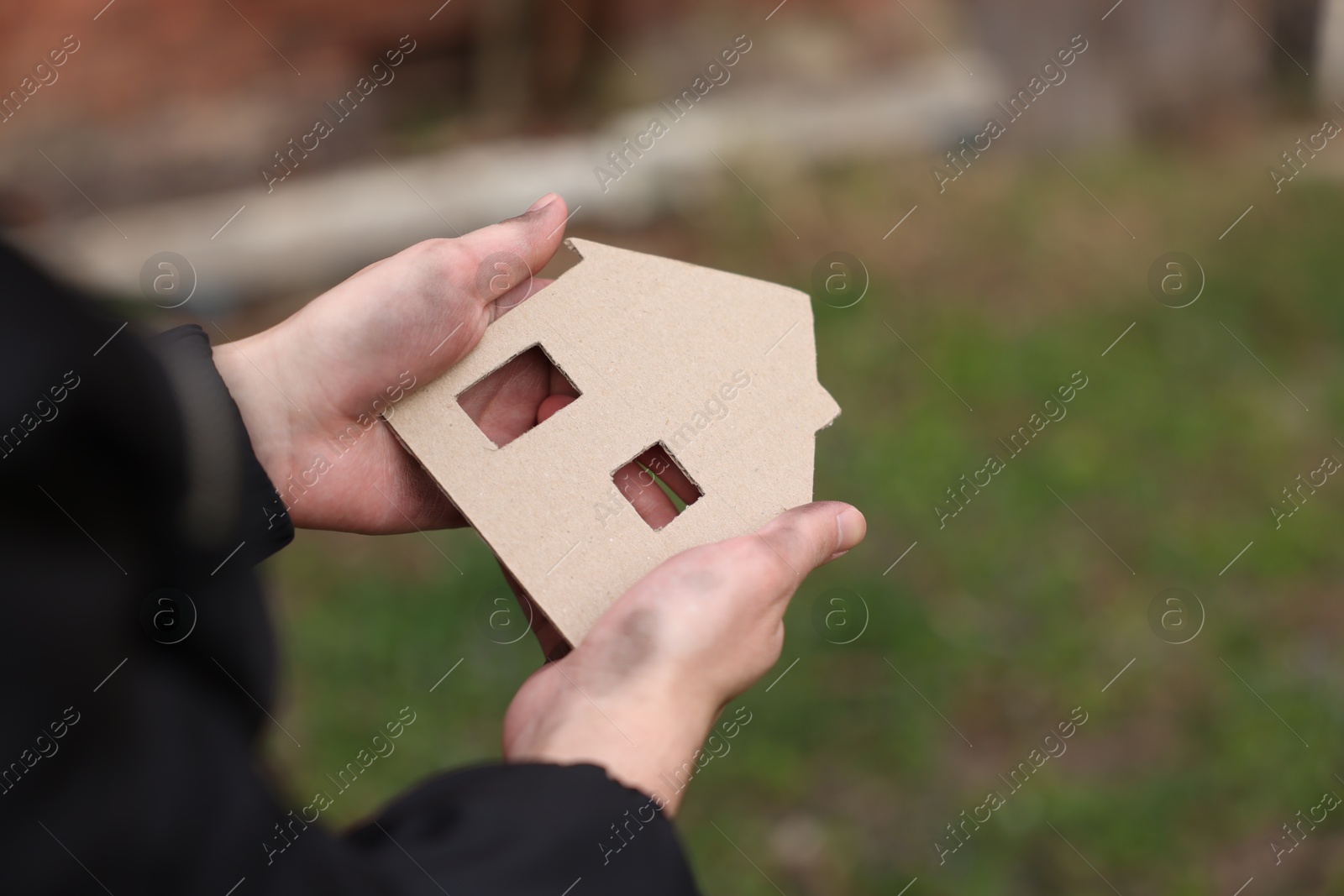 Homeless man with carton house figure outdoors, closeup Photo of Homeless man with carton house figure outdoors, closeup