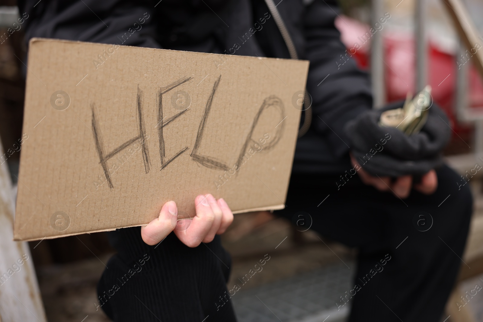 Homeless man holding sign with word Help and money outdoors, selective focus Photo of Homeless man holding sign with word Help and money outdoors, selective focus