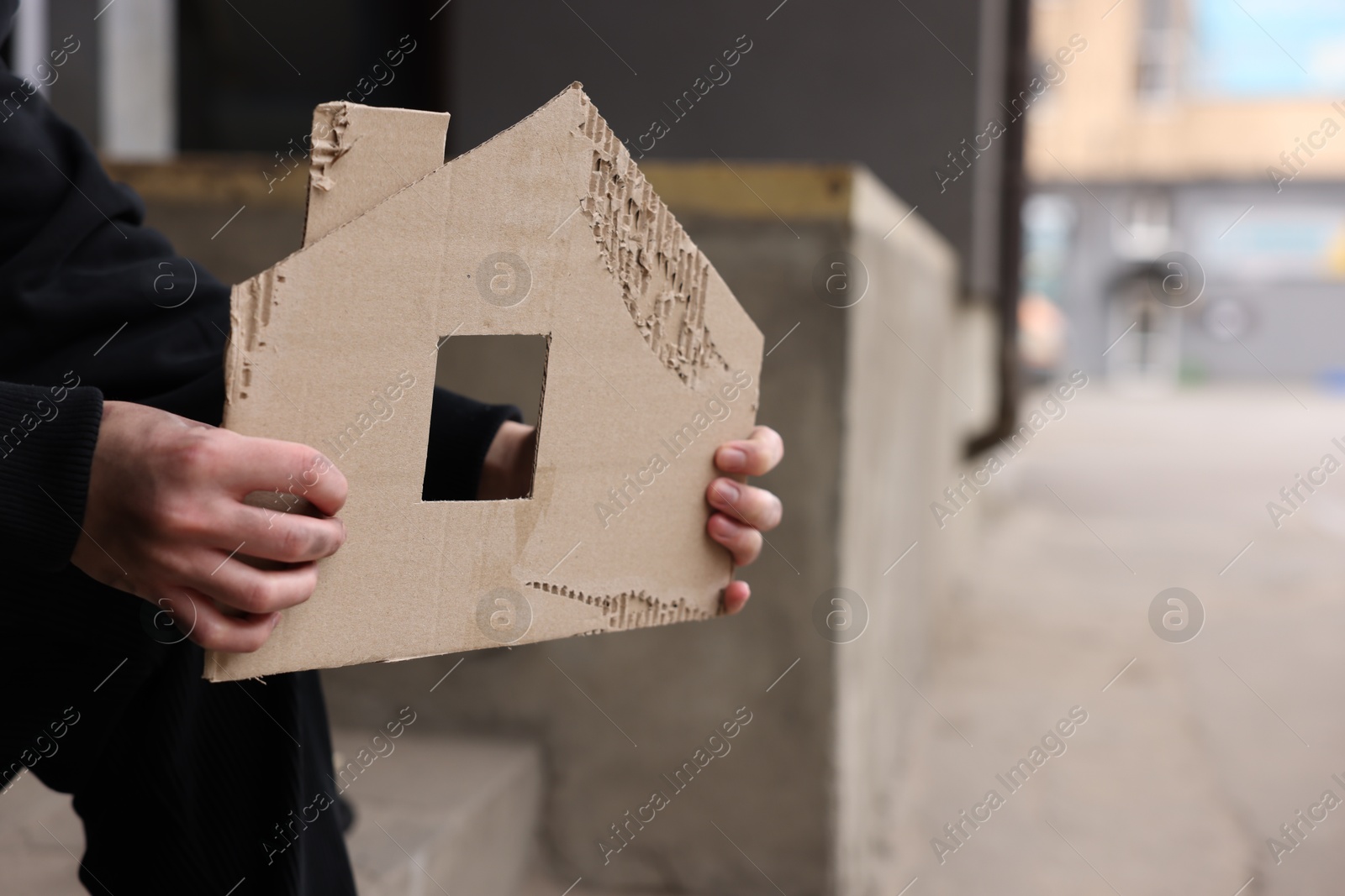 Homeless man with carton house figure outdoors, closeup Photo of Homeless man with carton house figure outdoors, closeup