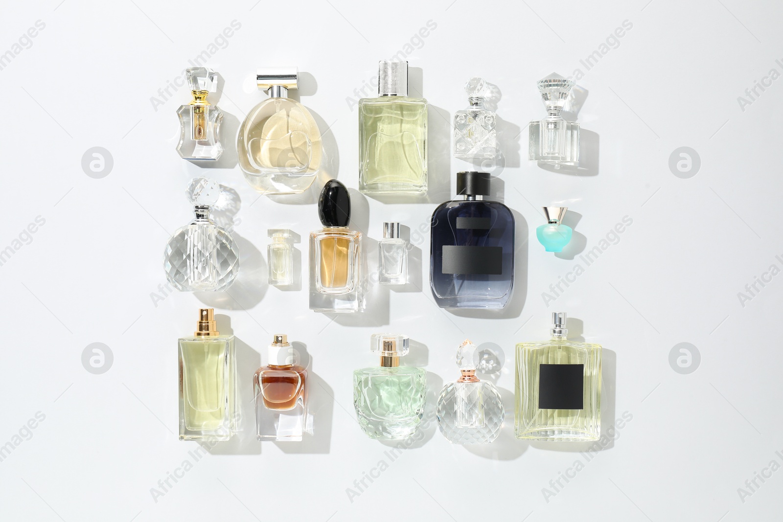 Bottles of various perfumes on light background, flat lay Photo of Bottles of various perfumes on light background, flat lay