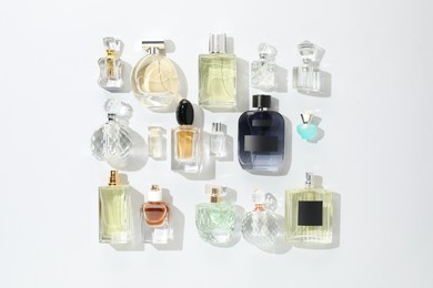 Photo of Bottles of various perfumes on light background, flat lay