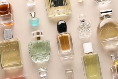 Photo of Bottles of various perfumes on beige background, flat lay