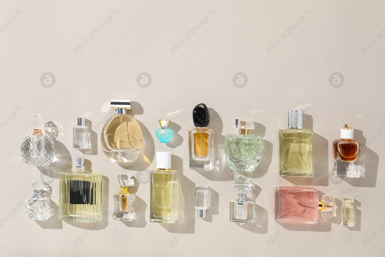 Bottles of various perfumes on beige background, flat lay. Space for text Photo of Bottles of various perfumes on beige background, flat lay. Space for text