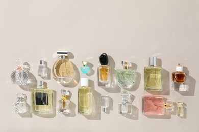 Photo of Bottles of various perfumes on beige background, flat lay. Space for text