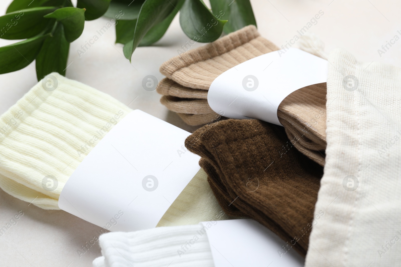 Different soft socks, bag and leaves on light beige background, closeup Photo of Different soft socks, bag and leaves on light beige background, closeup