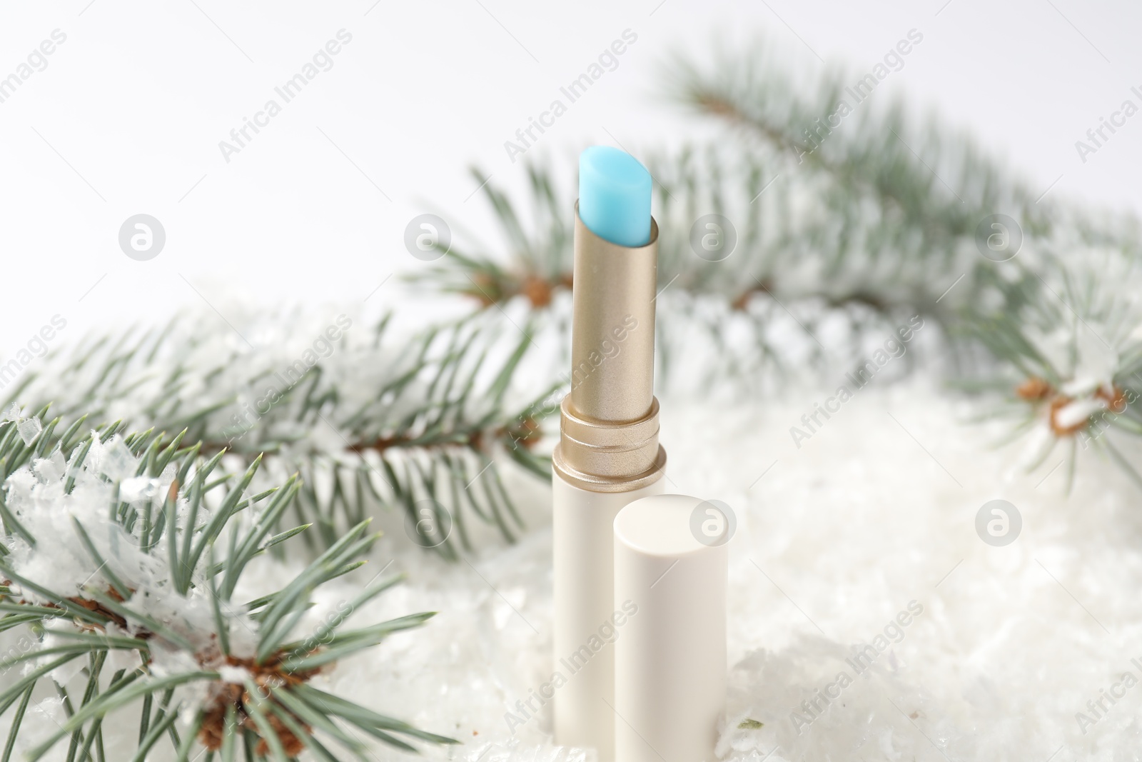 Moisturizing lip balm and fir tree branches on artificial snow against white background, closeup. Winter care Photo of Moisturizing lip balm and fir tree branches on artificial snow against white background, closeup. Winter care
