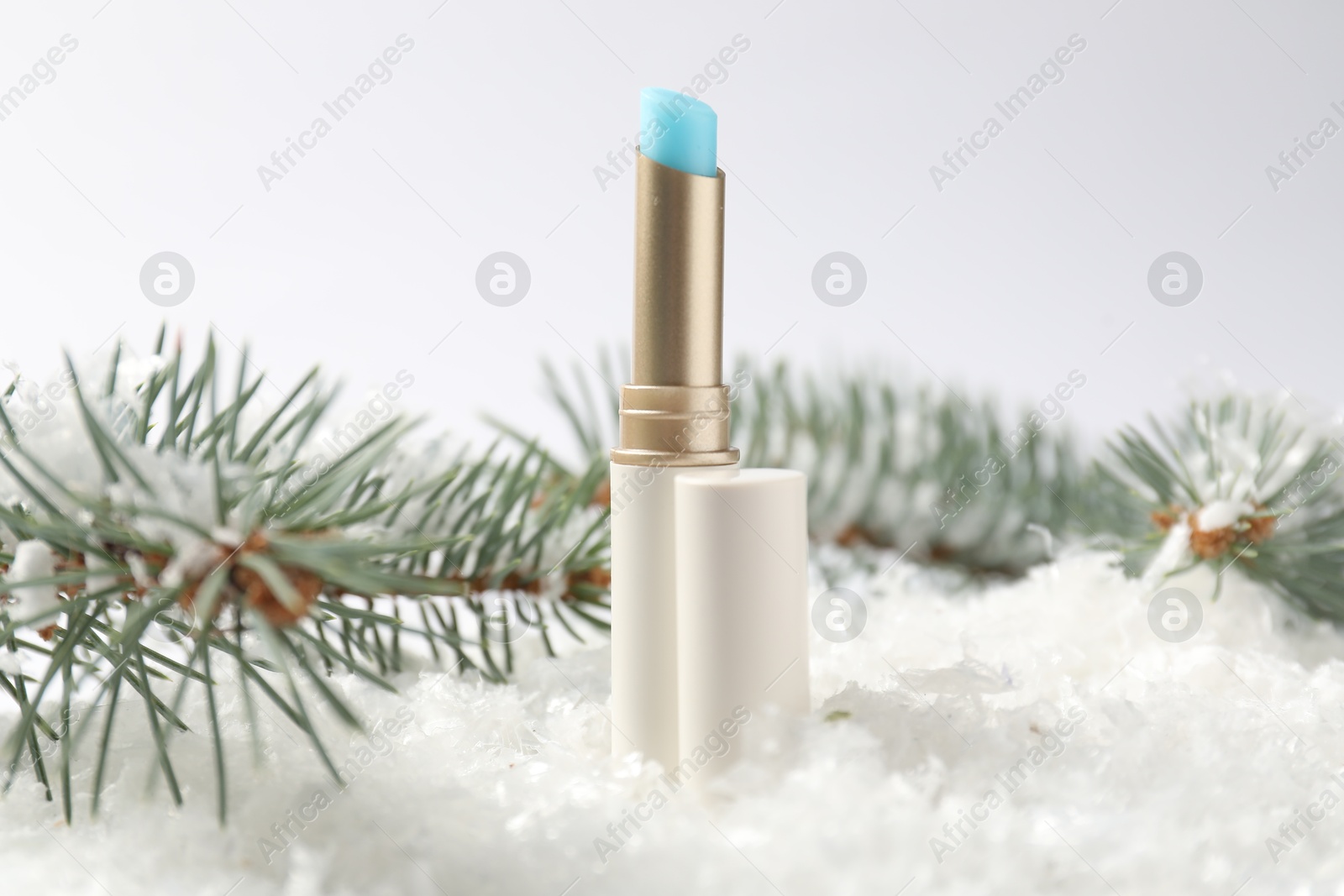 Moisturizing lip balm and fir tree branches on artificial snow against white background, closeup. Winter care Photo of Moisturizing lip balm and fir tree branches on artificial snow against white background, closeup. Winter care