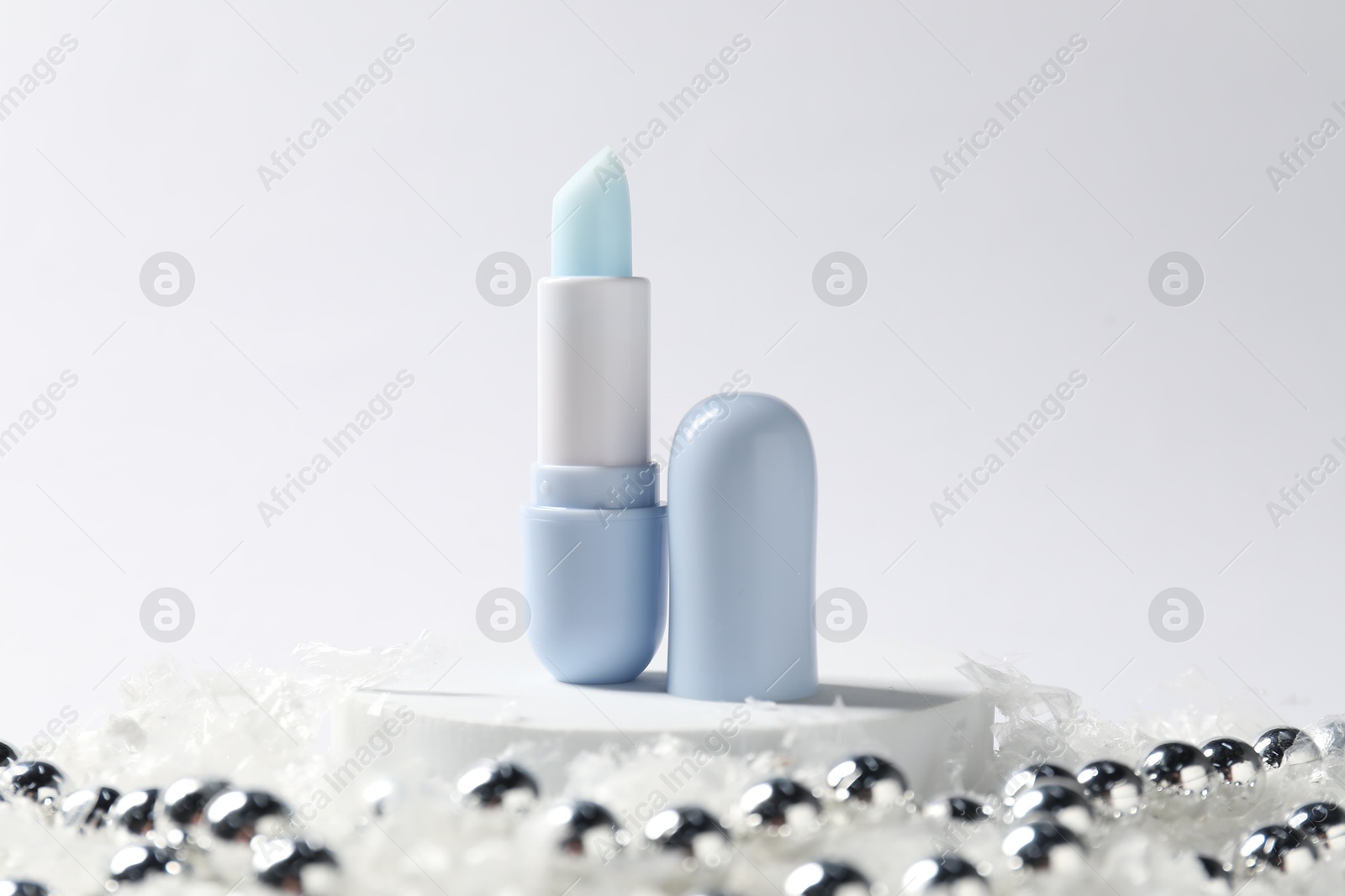 Moisturizing lip balm and Christmas decor on artificial snow against white background, closeup. Winter care Photo of Moisturizing lip balm and Christmas decor on artificial snow against white background, closeup. Winter care