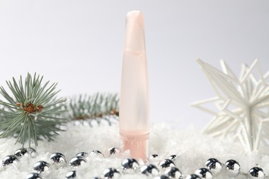 Photo of Moisturizing lip balm, Christmas decor and fir tree branches on artificial snow against white background, closeup. Winter care