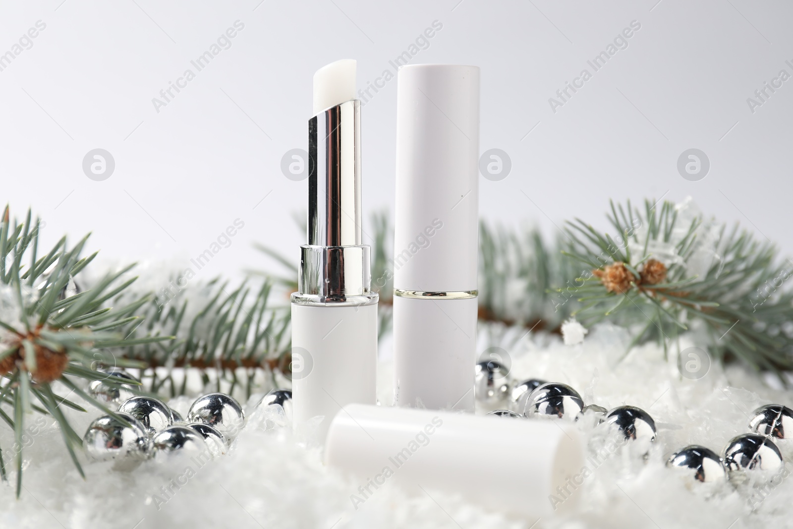 Moisturizing lip balms, Christmas decor and fir tree branches on artificial snow against white background, closeup. Winter care Photo of Moisturizing lip balms, Christmas decor and fir tree branches on artificial snow against white background, closeup. Winter care