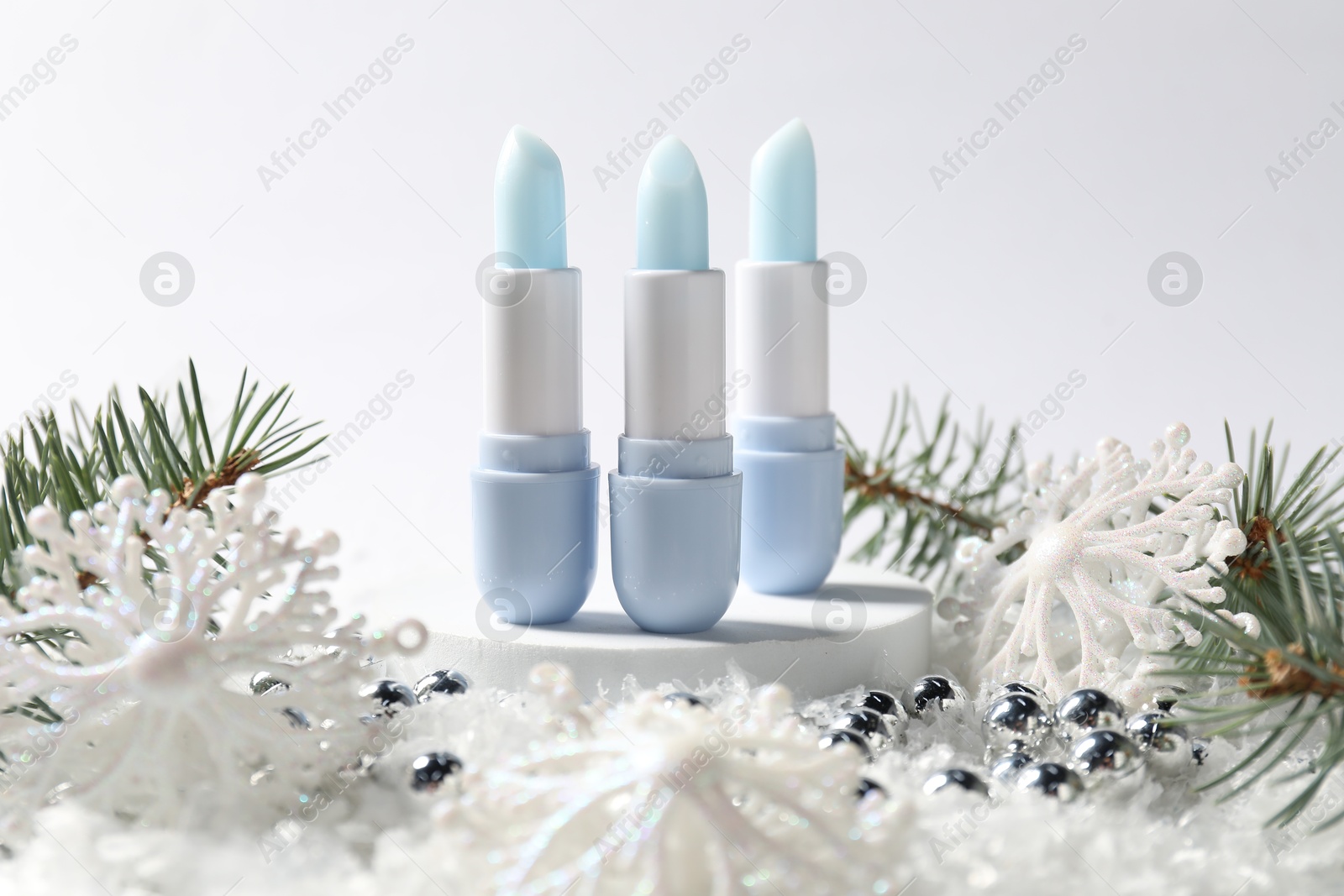 Moisturizing lip balms, Christmas decor and fir tree branches on artificial snow against white background, closeup. Winter care Photo of Moisturizing lip balms, Christmas decor and fir tree branches on artificial snow against white background, closeup. Winter care