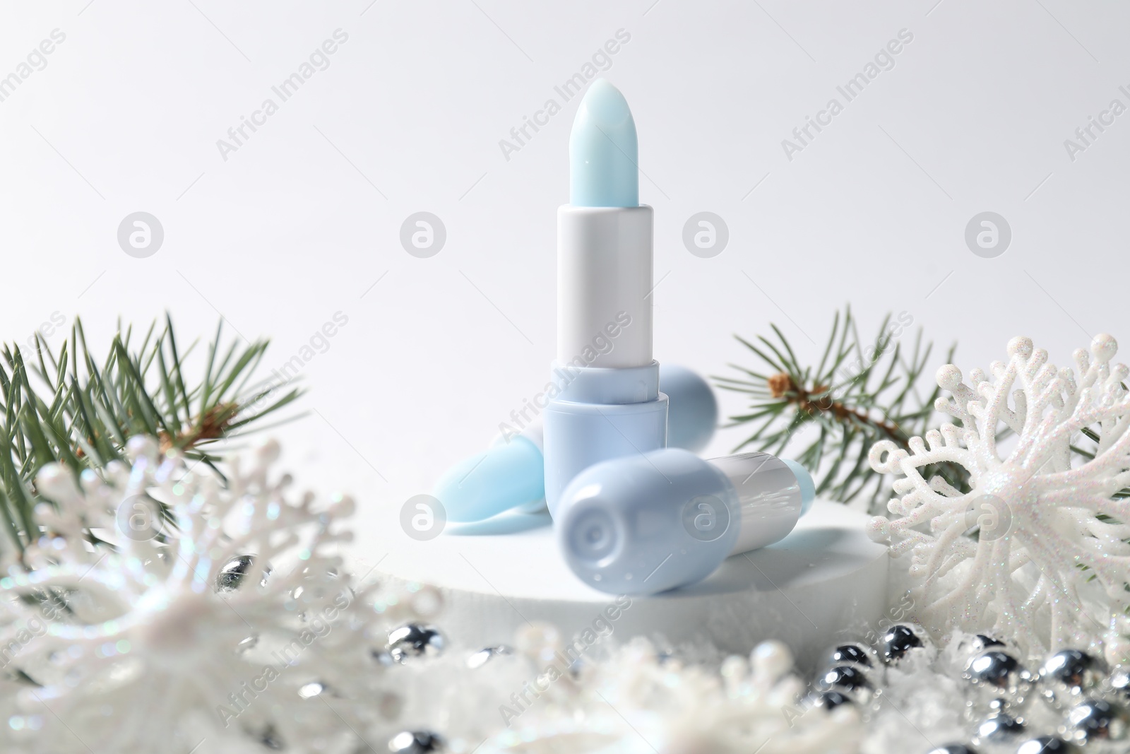 Moisturizing lip balms, Christmas decor and fir tree branches on artificial snow against white background, closeup. Winter care Photo of Moisturizing lip balms, Christmas decor and fir tree branches on artificial snow against white background, closeup. Winter care