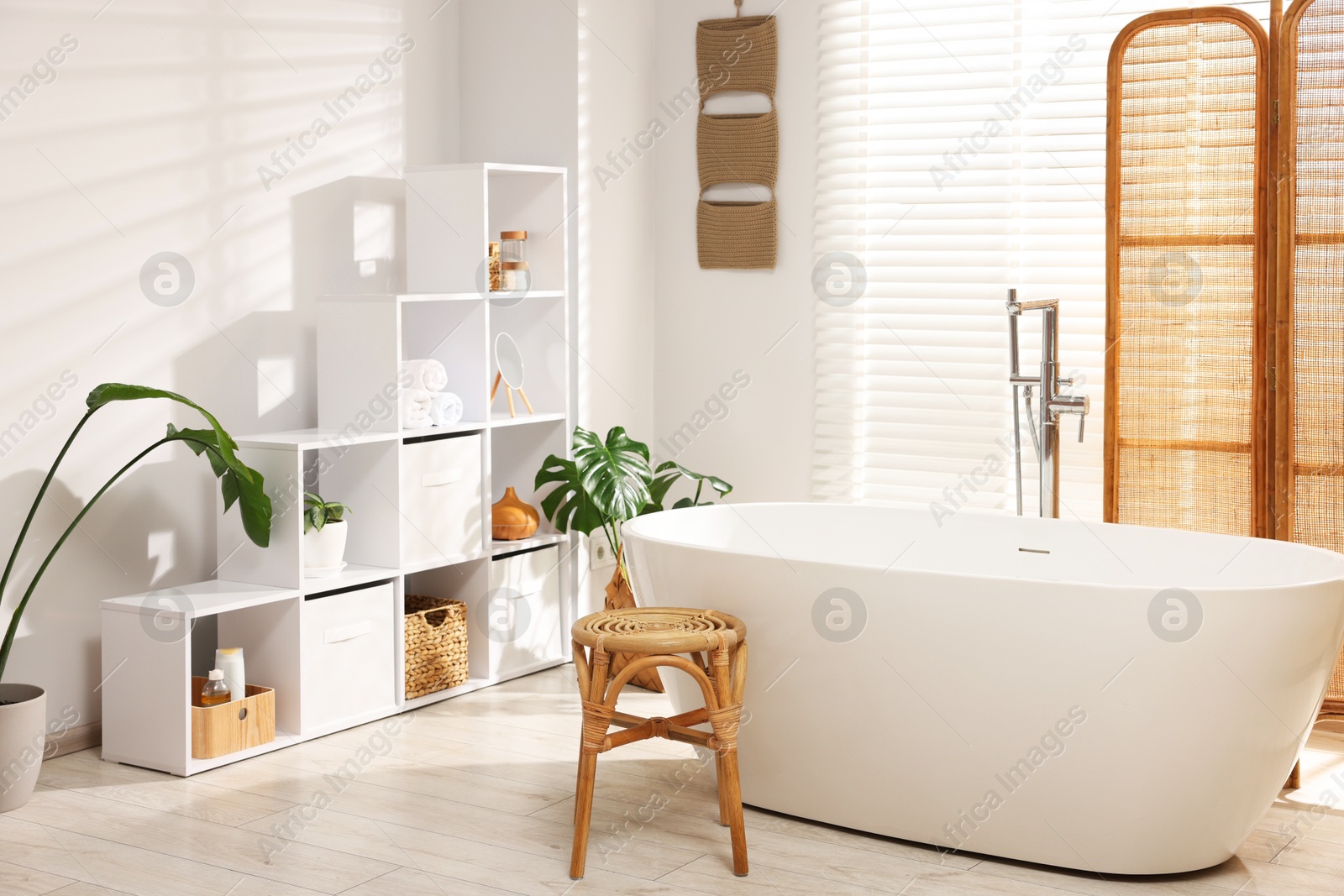 Stylish bathroom with shelving unit, bathtub and houseplants Photo of Stylish bathroom with shelving unit, bathtub and houseplants