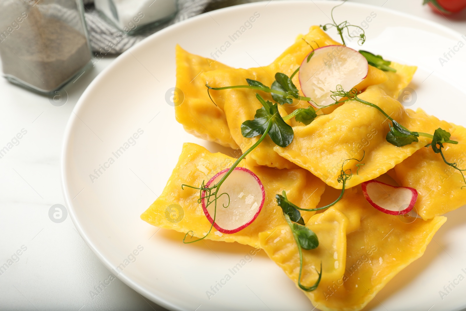 Delicious ravioli with microgreens and radish on light table, closeup Photo of Delicious ravioli with microgreens and radish on light table, closeup