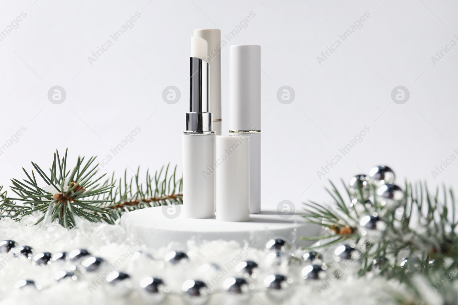 Moisturizing lip balms, Christmas decor and fir tree branches on artificial snow against white background, closeup. Winter care Photo of Moisturizing lip balms, Christmas decor and fir tree branches on artificial snow against white background, closeup. Winter care
