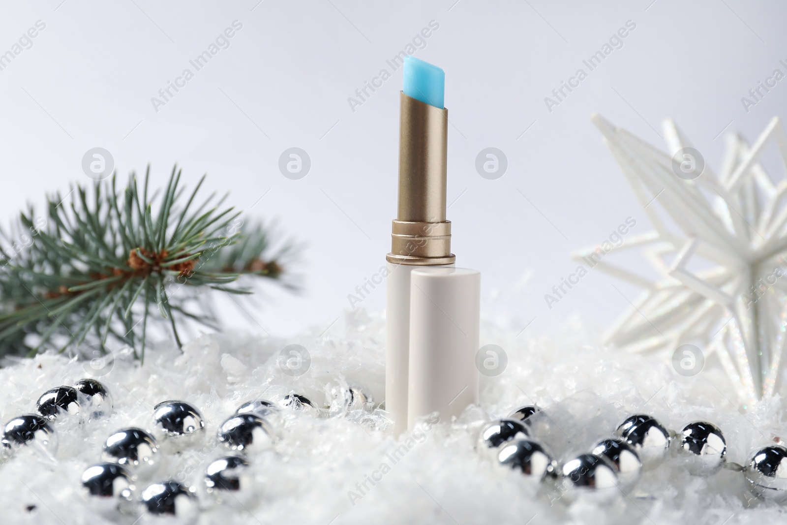 Moisturizing lip balm, Christmas decor and fir tree branches on artificial snow against white background, closeup. Winter care Photo of Moisturizing lip balm, Christmas decor and fir tree branches on artificial snow against white background, closeup. Winter care