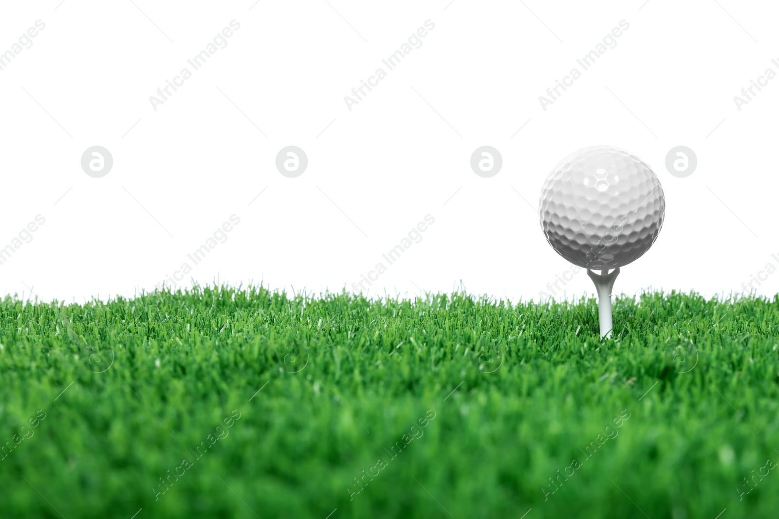 Golf ball, tee and green grass against white background Photo of Golf ball, tee and green grass against white background