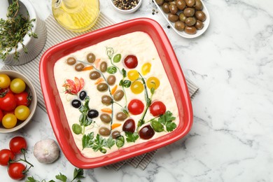 Photo of Raw focaccia with vegetables, olives and spices on white marble table, flat lay. Space for text