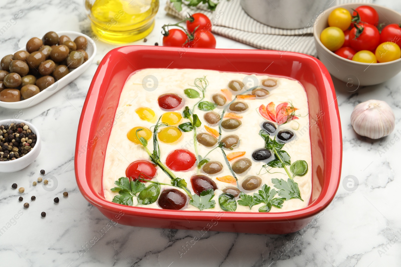 Raw focaccia with vegetables, olives and spices on white marble table, closeup Photo of Raw focaccia with vegetables, olives and spices on white marble table, closeup