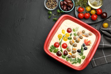 Photo of Raw focaccia with vegetables, olives and spices on black table, flat lay. Space for text