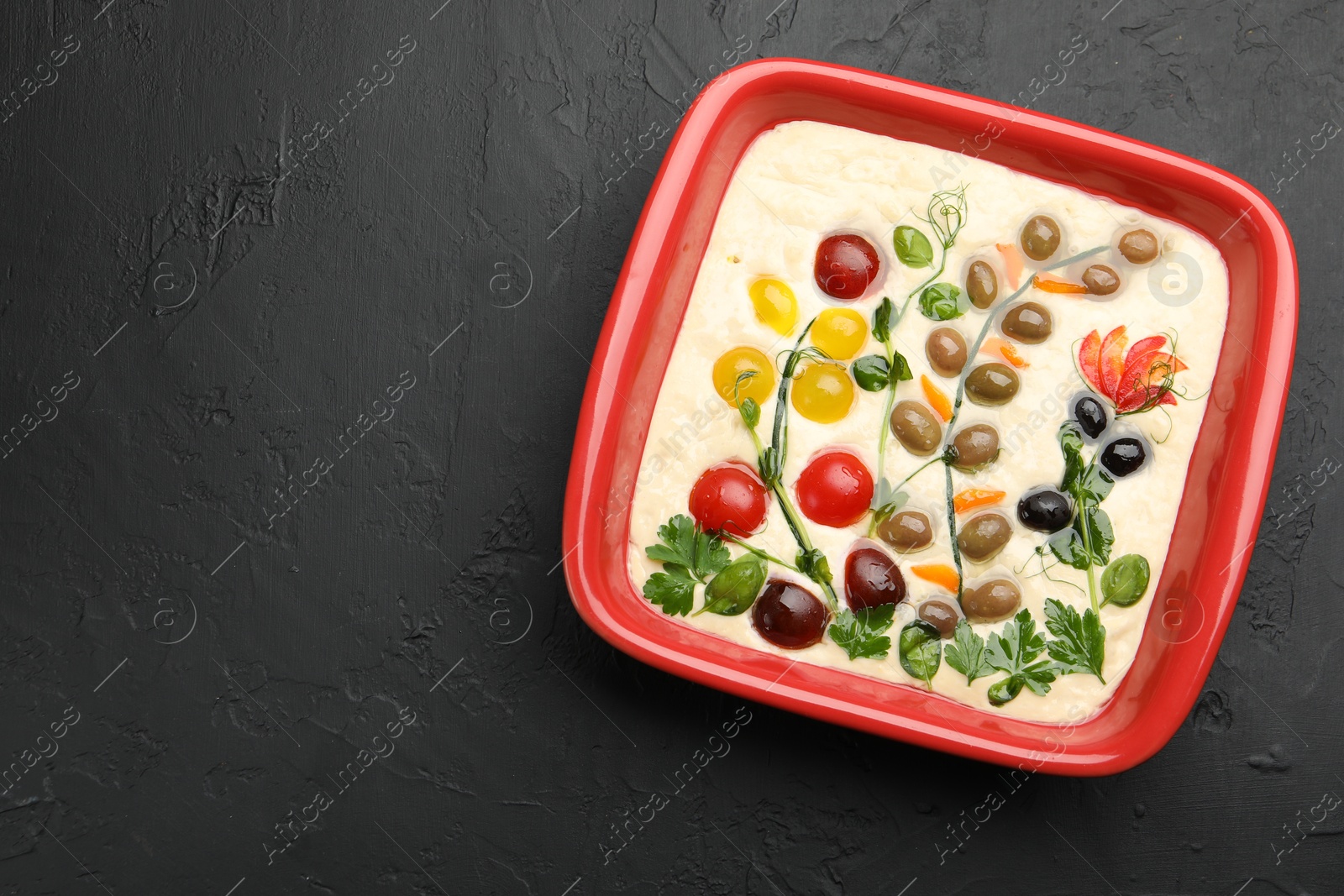 Raw focaccia with vegetables and olives in baking dish on black table, top view. Space for text Photo of Raw focaccia with vegetables and olives in baking dish on black table, top view. Space for text