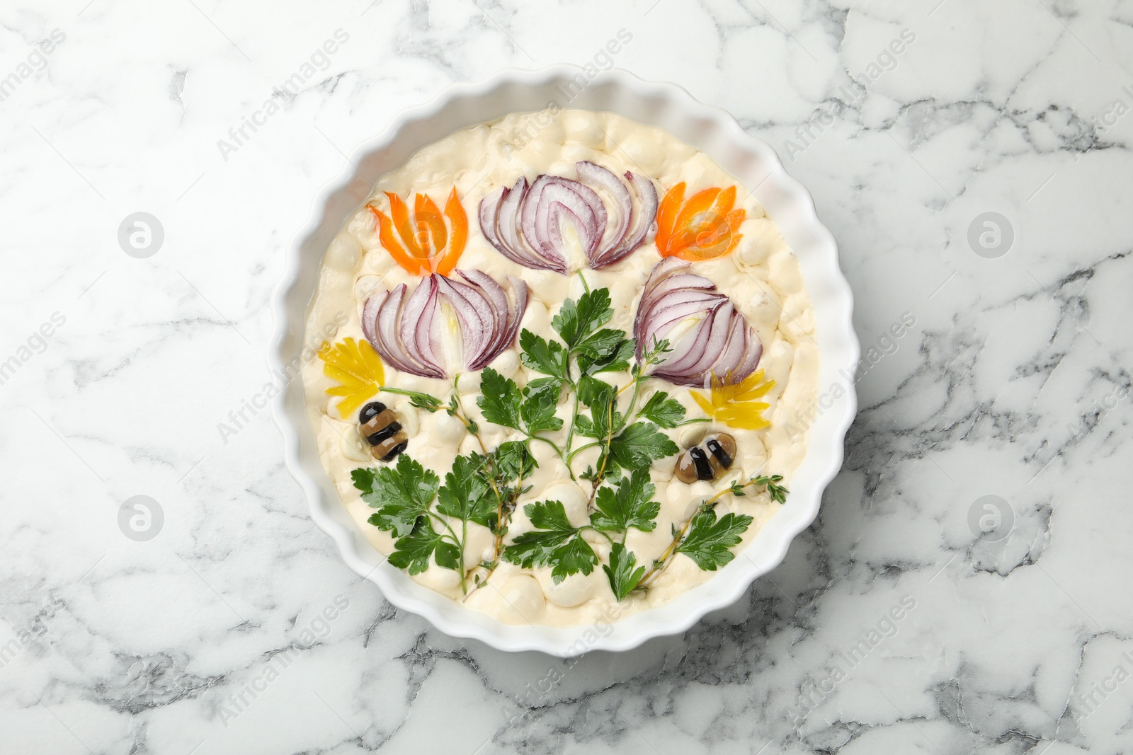 Raw focaccia with vegetables and olives in baking dish on white marble table, top view Photo of Raw focaccia with vegetables and olives in baking dish on white marble table, top view