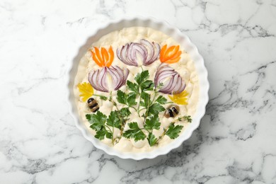 Photo of Raw focaccia with vegetables and olives in baking dish on white marble table, top view